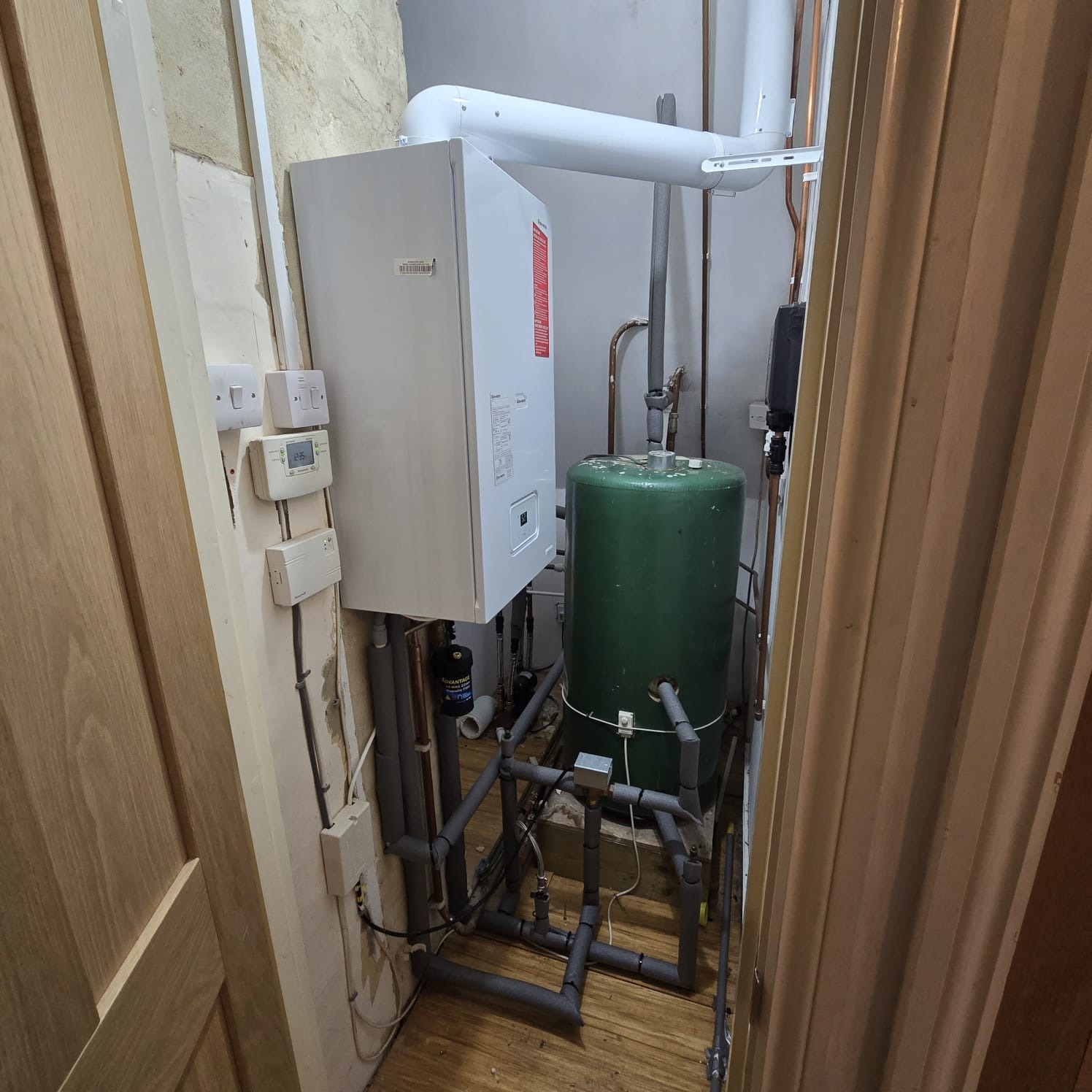 Central heating installation with boiler and hot water cylinder in a utility cupboard